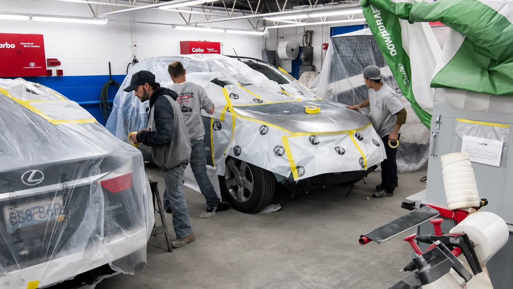 Technicians masking a vehicle before refinishing